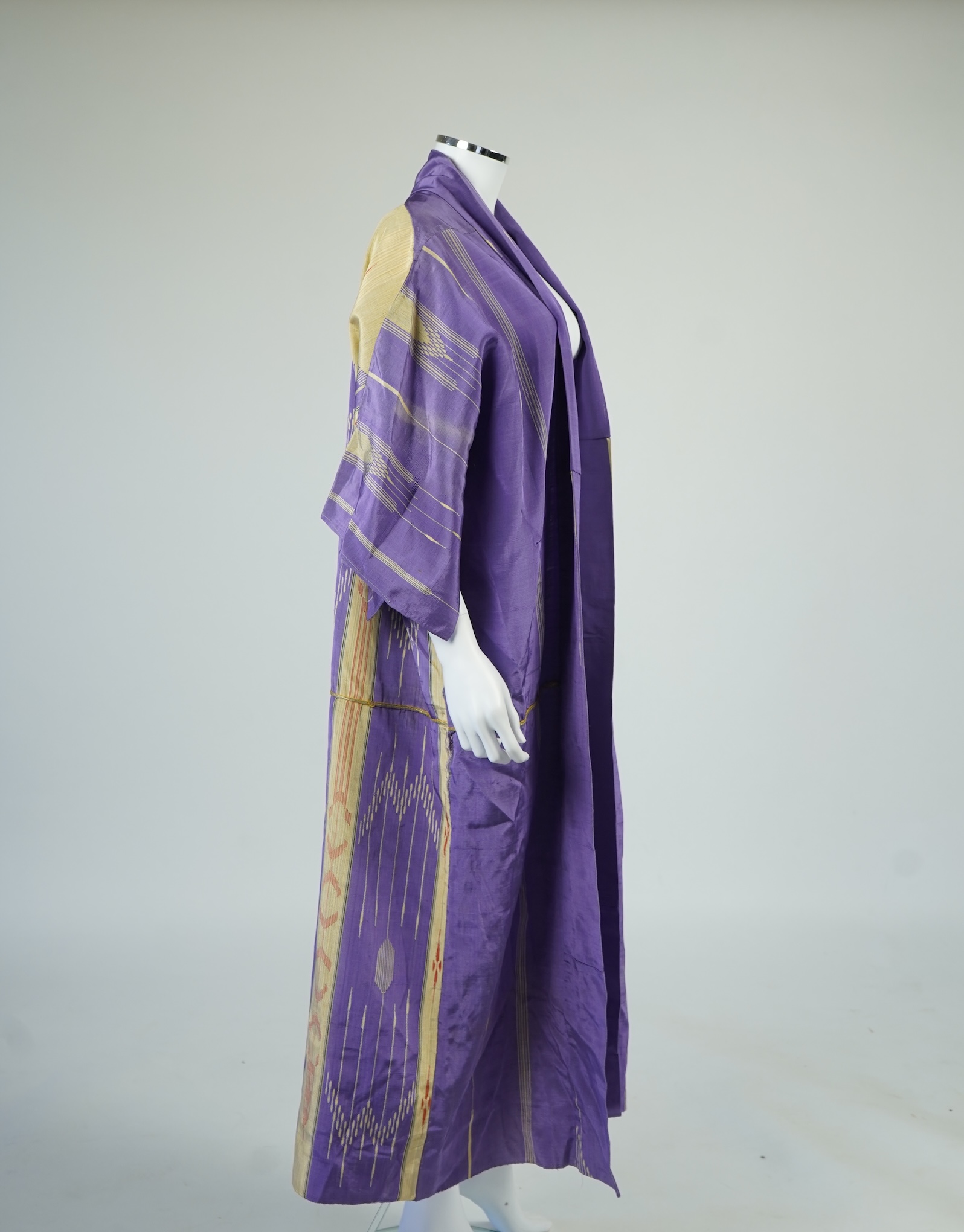 An early 20th century Syrian hand woven silk coat. Woven with stripes and geometric shapes in purple and yellow and red., 130 cm long. Condition - good, colours and fabric strong.